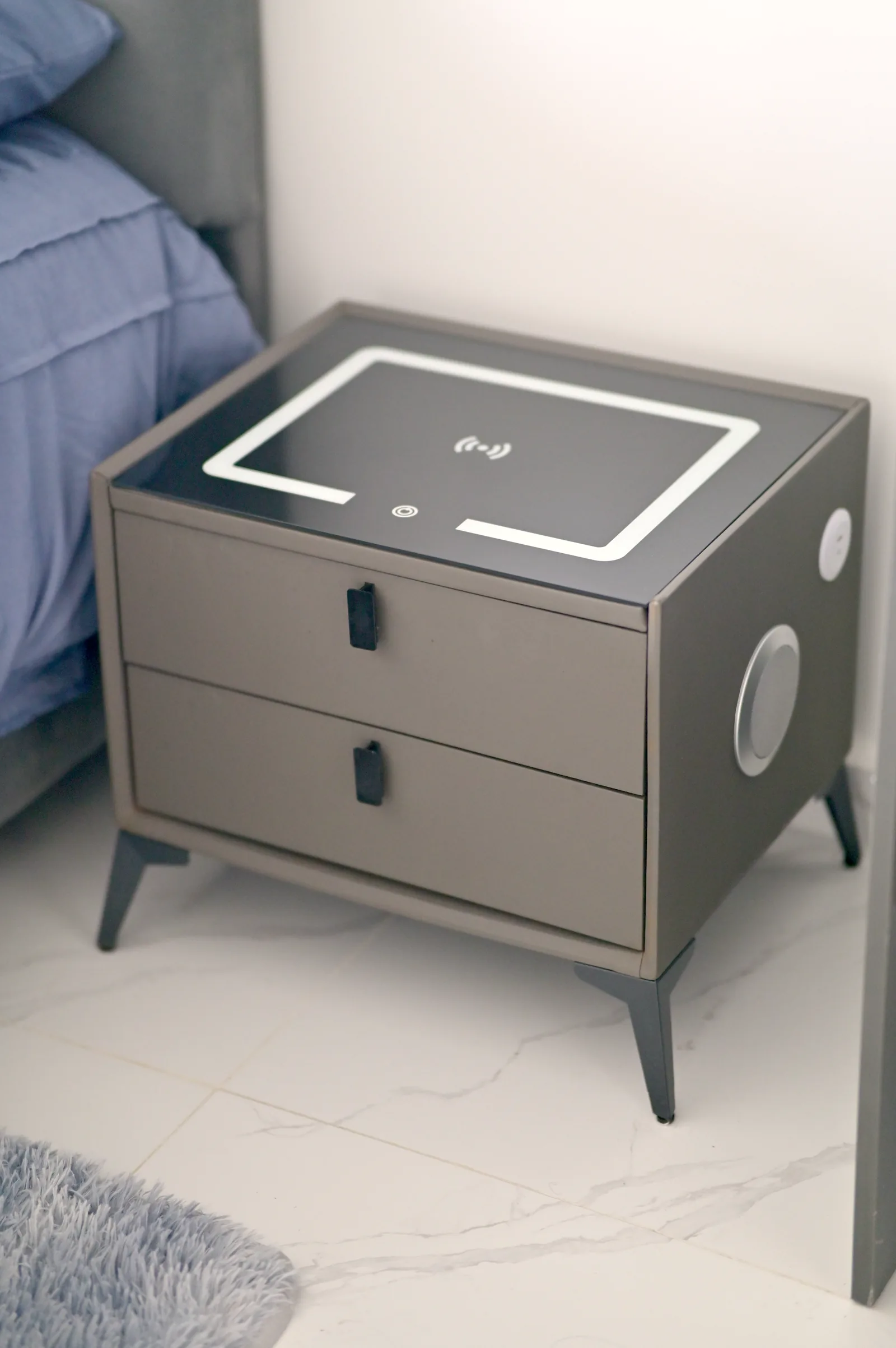 Mesa de noche con base de carga inalámbrica integrada en la tapa, junto a la cama.