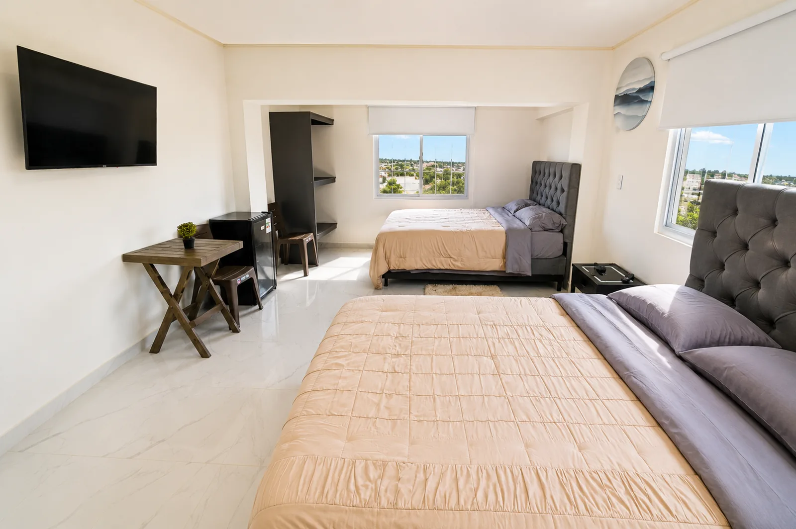 Habitación con dos camas, escritorio y ventanas hacia el pueblo.