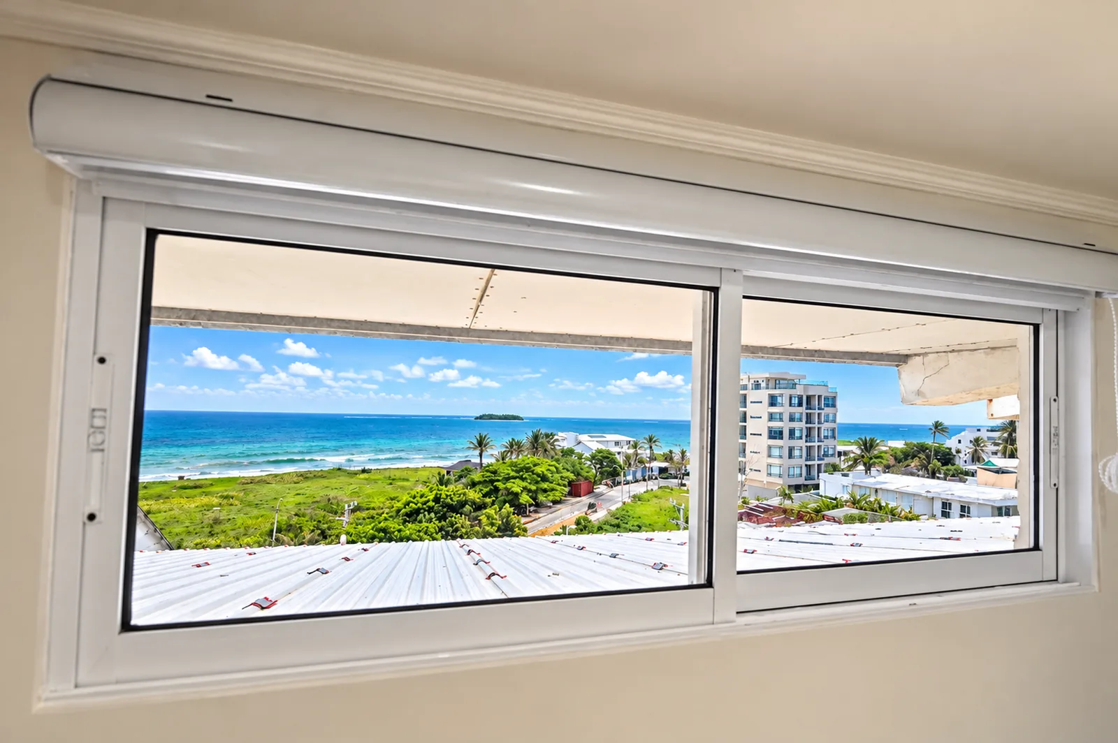 Ventana corrida de una habitación con el mar turquesa, el arrecife y Johnny Cay al fondo.