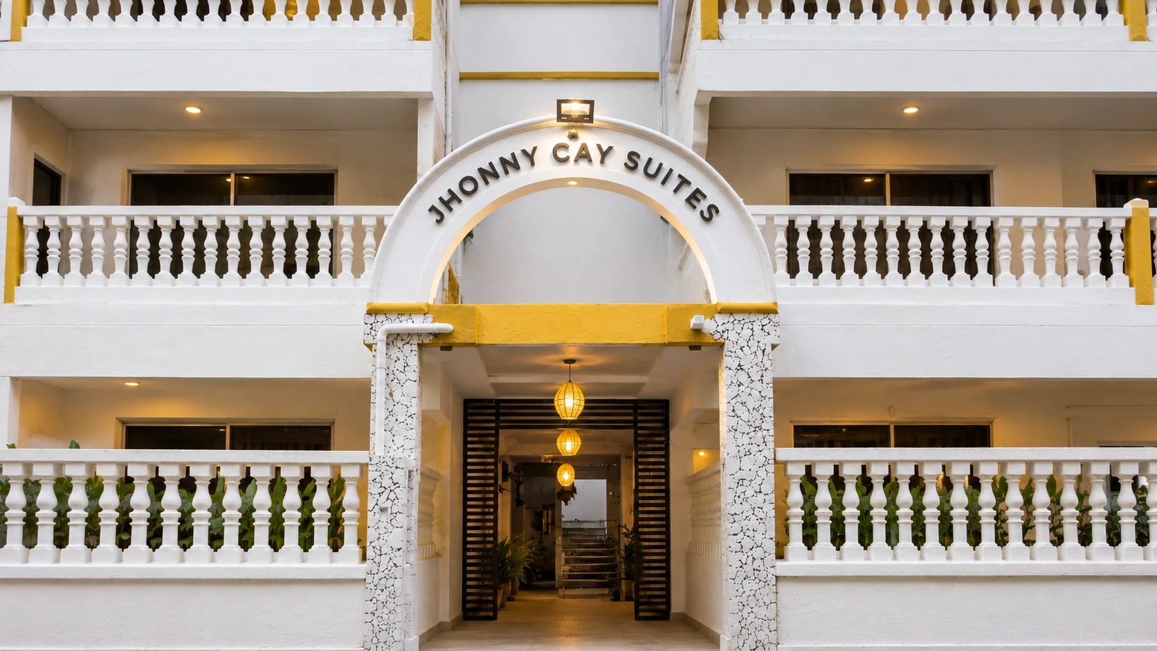 El arco de entrada con el letrero Jhonny Cay Suites y las lámparas de fibra.