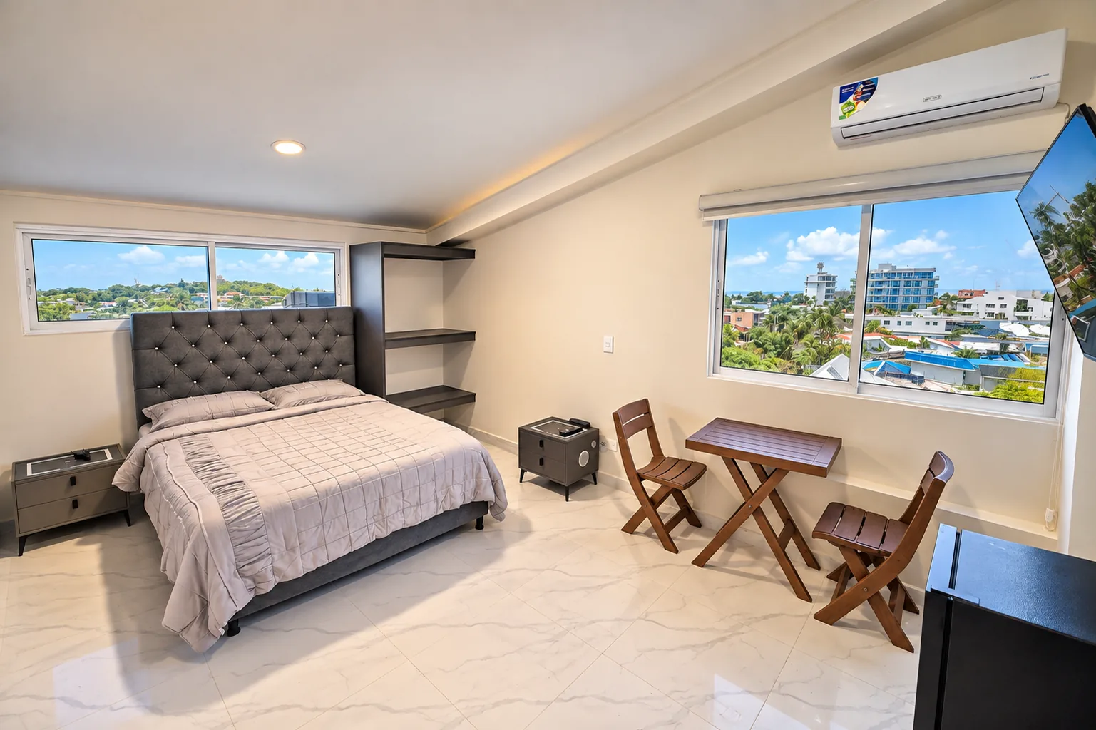 La suite con la cama doble, la mesa para dos junto a la ventana y el pueblo al fondo.