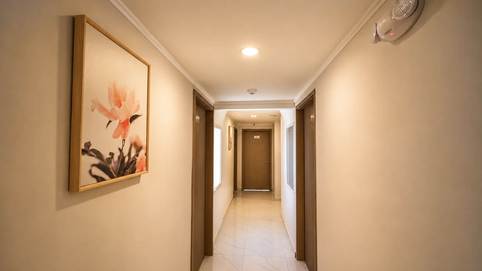 Corredor interior con puertas de madera y piso de mármol claro.