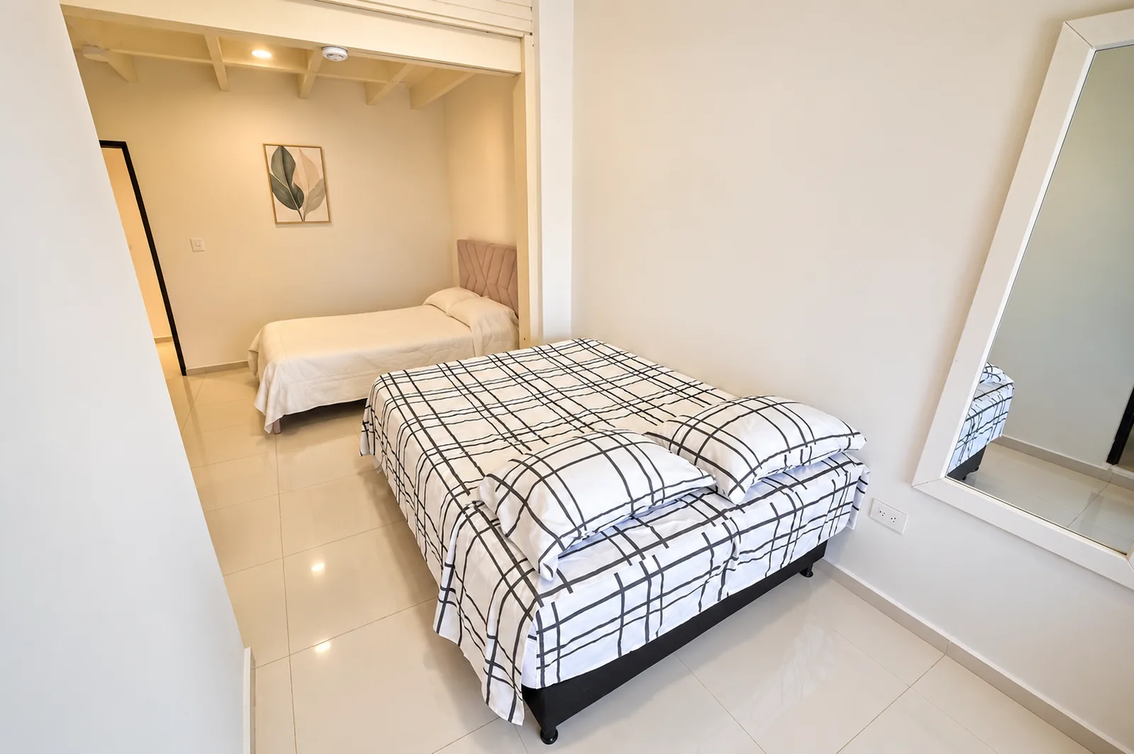 Apartamento de dos habitaciones: una cama doble en primer plano y, por el vano, la segunda cama en el cuarto de atrás.